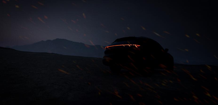 A car is dimly lit only leaving the illuminated INFINITI logo and headlights visible.