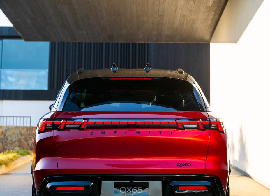 Rear view of the 2027 INFINITI QX65 parked under a covered area.