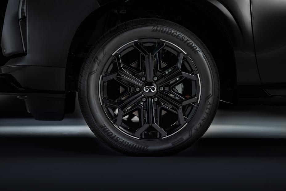 Close-up of a car wheel with a black, intricate design and the Infiniti logo at the center.