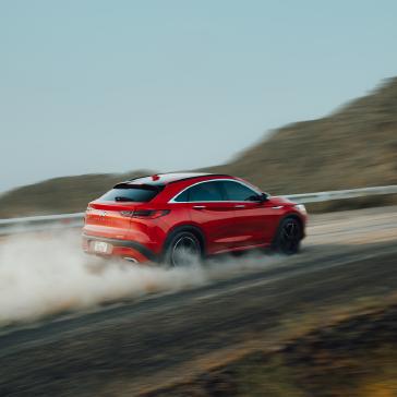 Rear view of compact red SUV parked on a dirt road