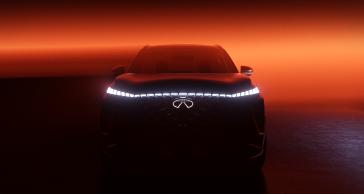 Front view of the QX65 Monograph in a room lit in red, the headlights illuminate brightly.