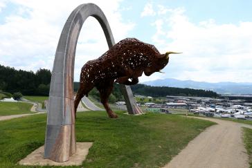 Full image of Image of a brown bull statue with gold horns standing on its hind legs under a silver arch