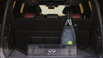 Cajuela abierta de un vehículo INFINITI con un organizador y equipo de tenis, incluyendo raquetas y una pelota, mostrada desde la parte trasera.