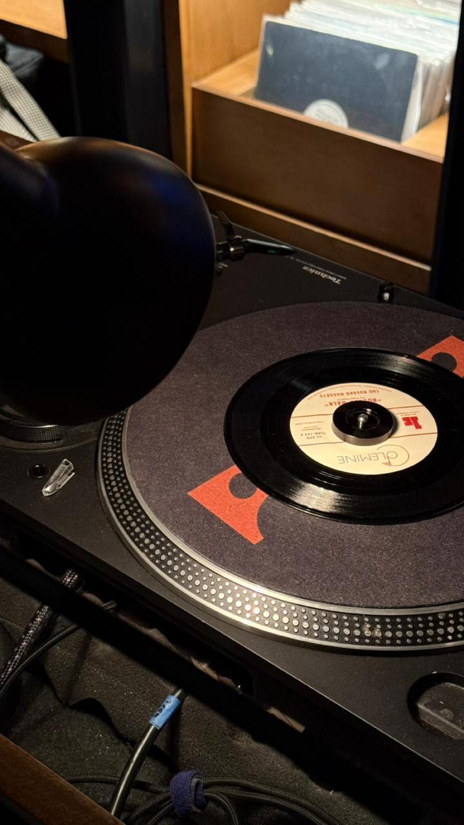 Primer plano de una tornamesa con un disco de vinilo reproduciéndose en un espacio interior con luz tenue, tomada durante el evento de INFINITI Membership Experience.