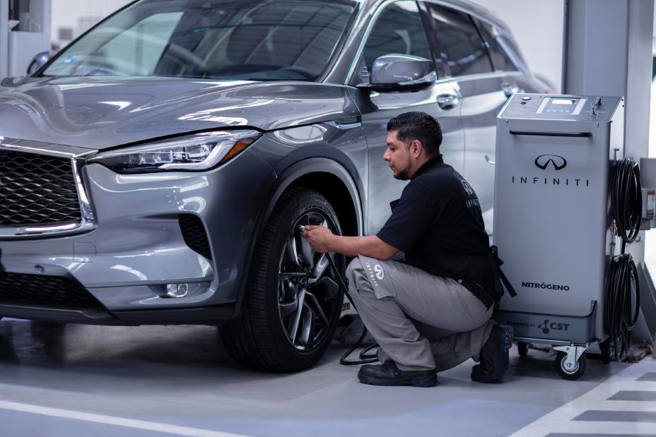 Técnico especializado de INFINITI inflando las llantas de un vehículo con nitrógeno, mostrando el cuidado especializado y la tecnología aplicada para mejorar la eficiencia y seguridad.