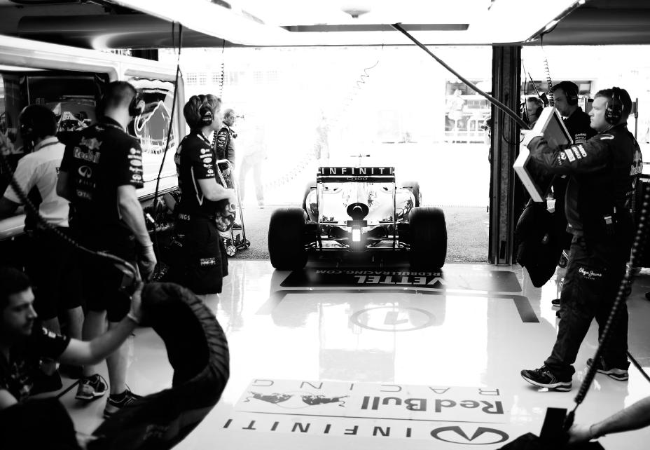 A black and white photo of multiple people surrounding a race car