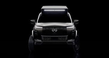 Front view of the INFINITI QX80 Terrain Spec in the dark, the headlights, emblem and light bar are illuminated.