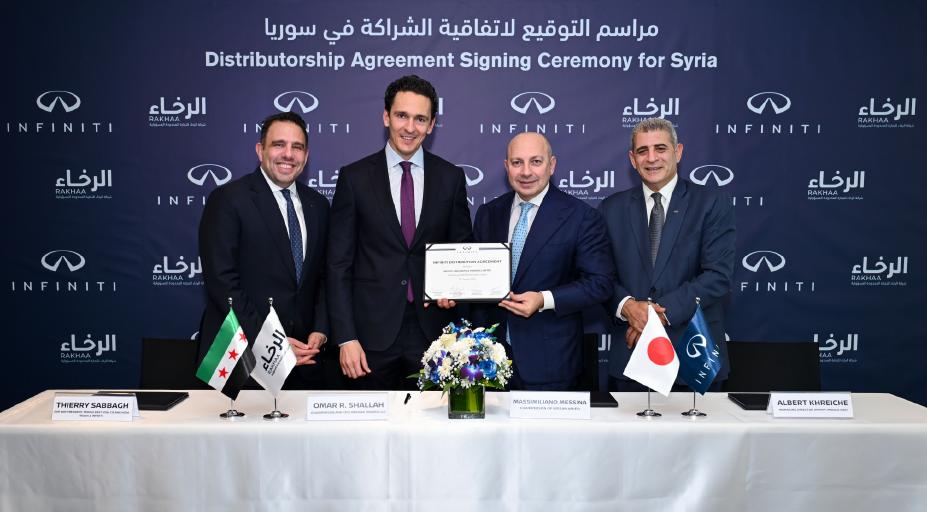 Front-facing group of executives posing with a signed agreement at a formal corporate ceremony