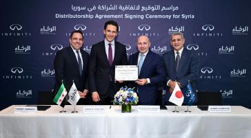 Front-facing group of executives posing with a signed agreement at a formal corporate ceremony