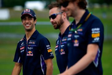 2 INFINITI team members walking next to driver as he smiles at the camera