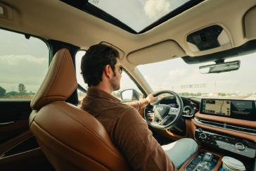 Interior de una INFINITI QX60 visto desde los asientos traseros mientras dos personas disfrutan un trayecto como parte de INFINITI Membership Experience.