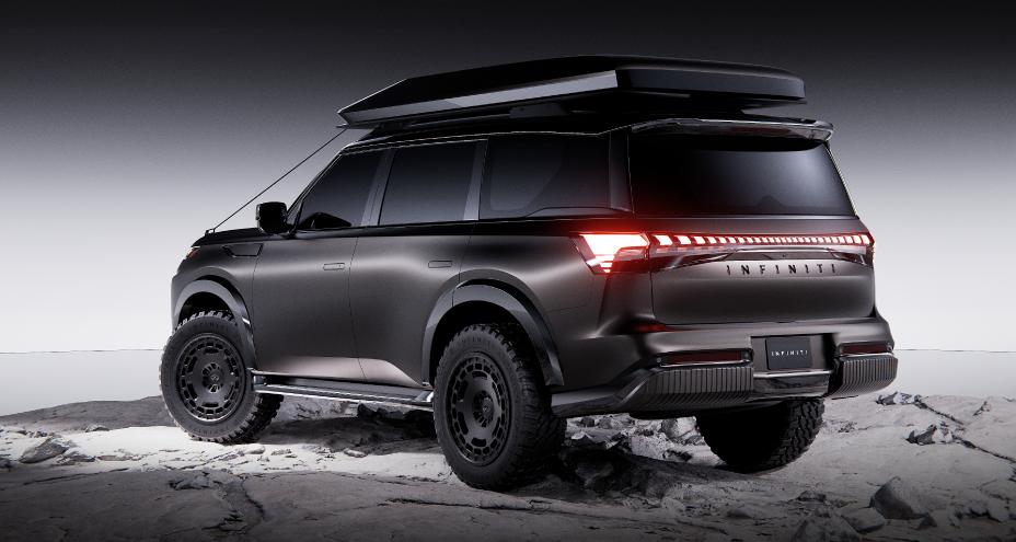 Rear view of the INFINITI QX80 Terrain Spec parked on rocky terrain against a gradient background.