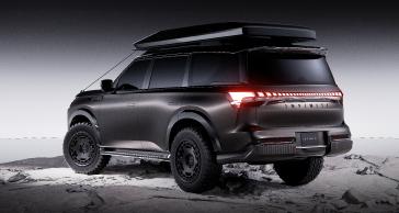 Rear view of the INFINITI QX80 Terrain Spec parked on rocky terrain against a gradient background.