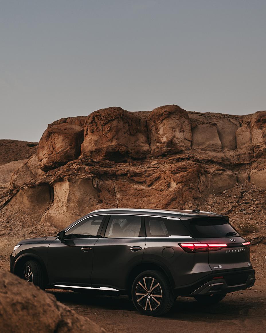 Black SUV in front of rugged desert rock formations