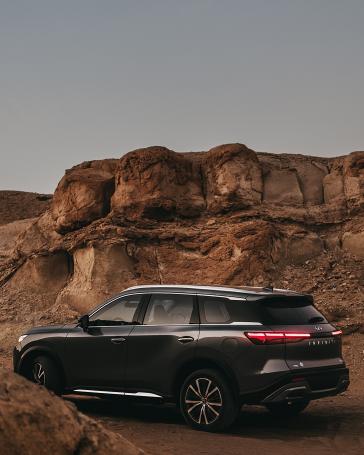 Black SUV in front of rugged desert rock formations
