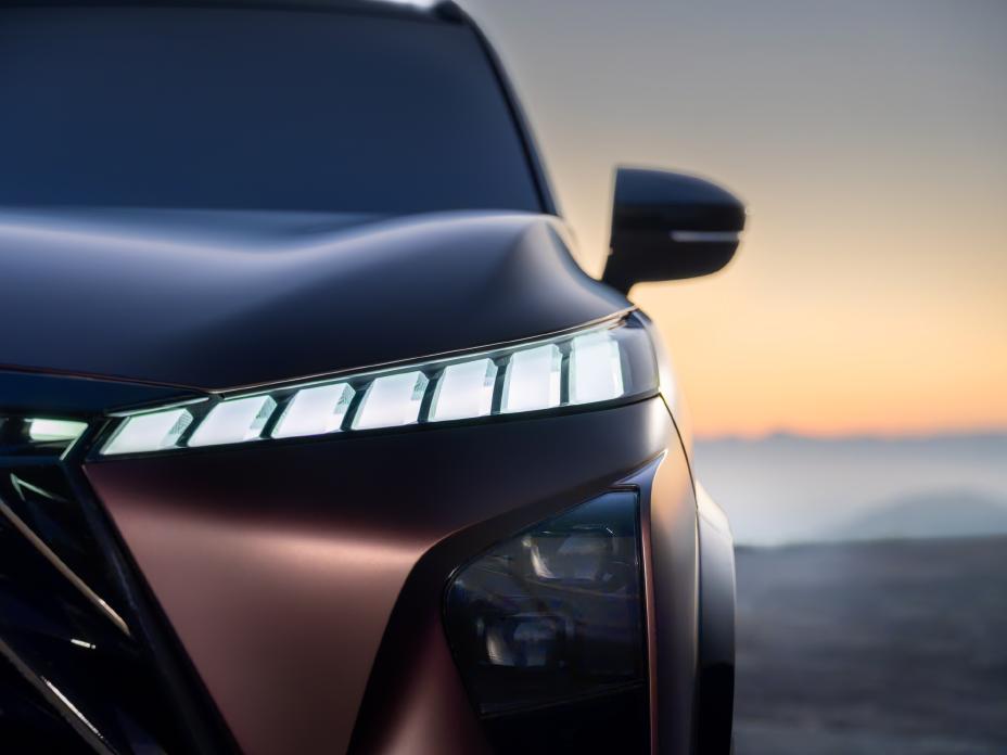 Close up front view of the illuminated headlight on the QX65 Monograph at sunset.