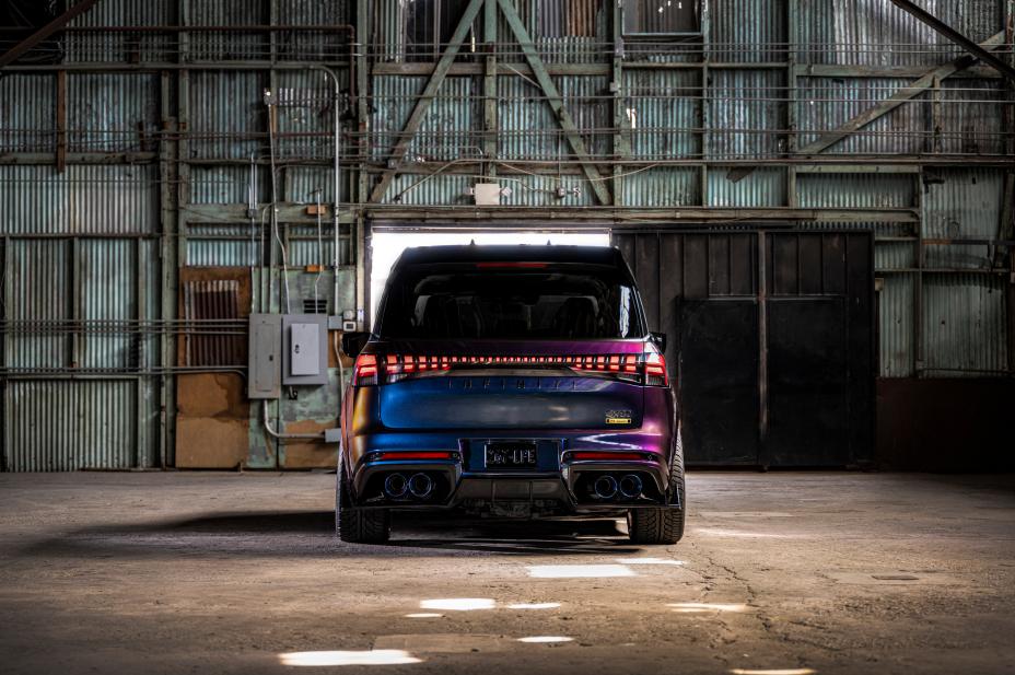 Rearview of the INFINTI QX80 R-Spec build parked inside a warehouse, light shines through and reflects off the paint.
