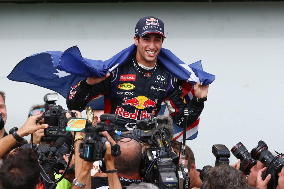 A man surrounded by cameras with a blue flag draped over his shoulders