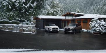 Un INFINITI QX80 et un QX60 de 2026 stationnés dans une allée devant une maison moderne sous la neige.