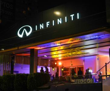 Fachada iluminada del concesionario INFINITI Universidad por la noche, destacando su nueva identidad visual.