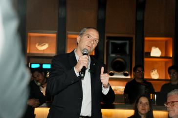 Imagen de una presentación realizada en un lugar ambientado con luz tenue, mostrando a una persona hablando frente a asistentes como parte del lanzamiento de INFINITI Membership Experience.