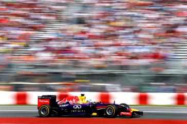 Infiniti F1 car driving the tack while the fans look on.