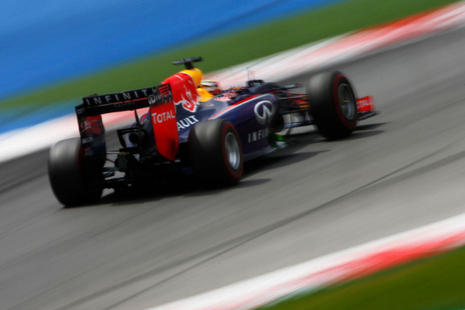 Rear view of multicolored Infiniti Red Bull car driving on the track.