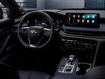 A view from the rear passenger seats of the steering, dashboard, display and controls inside the 2026 INFINITI QX60 SPORT.