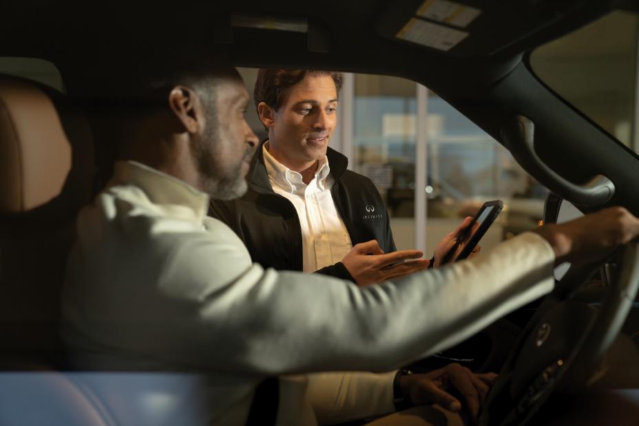 Conductor de INFINITI siendo atendido por un asesor en un entorno profesional, destacando el servicio personalizado del programa INFINITI Protect.