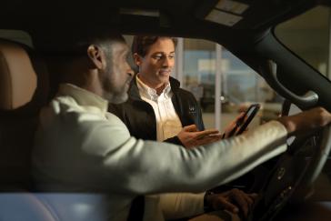 Conductor de INFINITI siendo atendido por un asesor en un entorno profesional, destacando el servicio personalizado del programa INFINITI Protect.