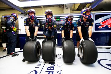 Four crew members rolling four tires