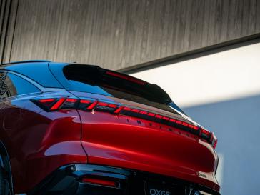 Lower angled rear view of the 2027 INFINITI QX65 with a modern buolding behind.