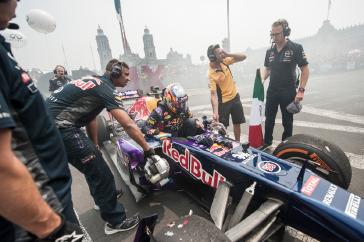 People standing around the Formula One race car.