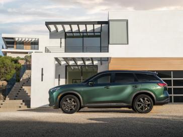 Left profile view of a 2026 INFINITI QX60 parked in front of a modern building.