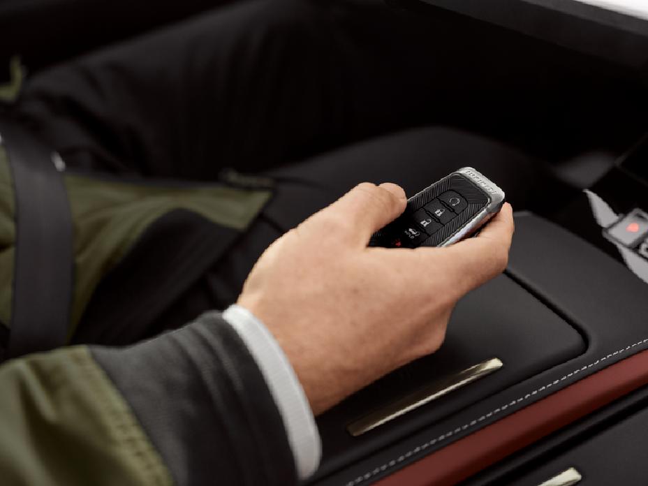 Mano sosteniendo la llave inteligente dentro de un vehículo INFINITI, destacando los acabados premium del interior.