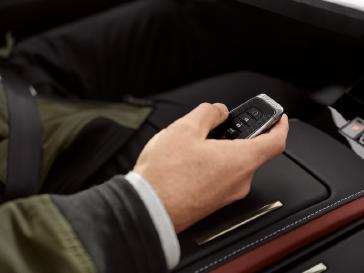 Mano sosteniendo la llave inteligente dentro de un vehículo INFINITI, destacando los acabados premium del interior.