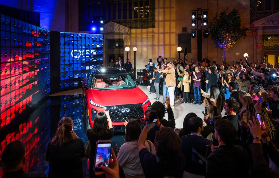 A crowd of people standing around the 2027 INFINITI QX65 with their cameras out.
