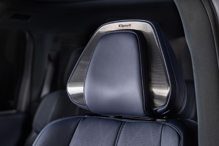 Close-up of the headrest in the 2026 INFINITI QX80, upholstered in dark blue perforated leather with metallic accents. The brand name "Klipsch" is prominently displayed on the headrest.