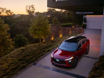 Aerial view of the 2027 INFINITI QX65 at sunset, the headlights are illuminated.