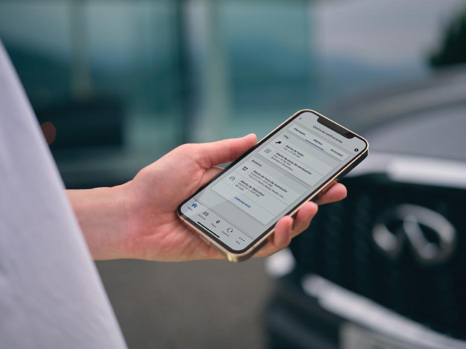 Un Invitado INFINITI utiliza MiINFINITI App desde su smartphone mientras se encuentra fuera del vehículo, ilustrando cómo la conectividad personalizada será clave en la evolución del lujo en 2026.