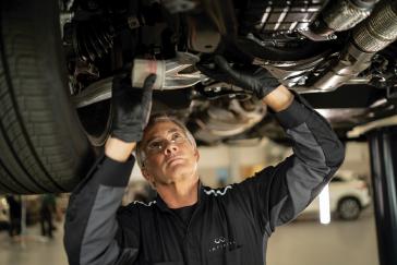 Técnico de INFINITI inspeccionando una unidad en un entorno profesional, destacando el enfoque detallado y experto del programa INFINITI Protect.
