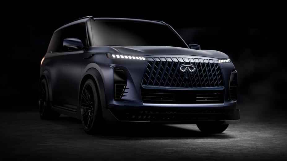 Front right 3/4 view of the INFINITI QX80 Track Spec mostly in the dark, the headlights are illuminated.