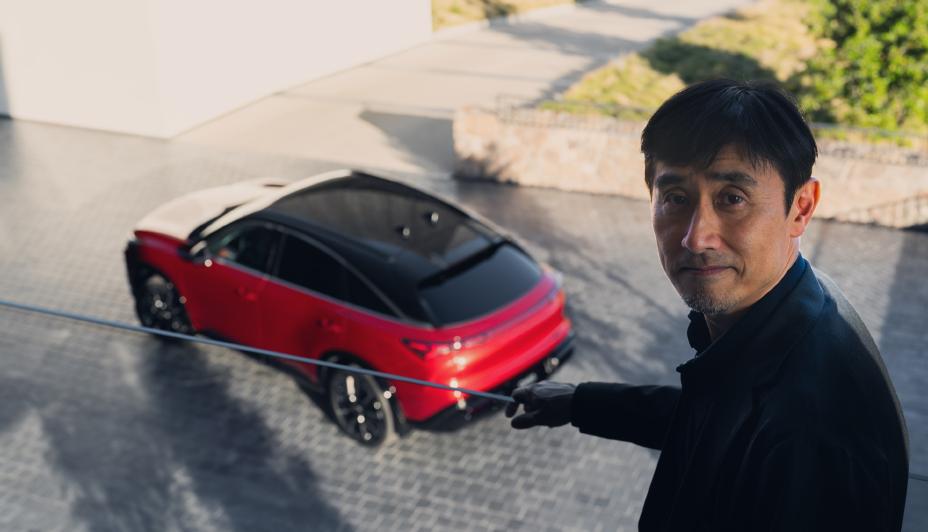 A man standing on a balcony overlooking the 2027 INFINITI QX65 in the daytime.