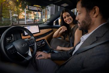 Pareja conversando cómodamente en el interior de una INFINITI QX60, rodeados de un ambiente amplio, elegante y silencioso, mientras disfrutan un momento de conexión durante el viaje.