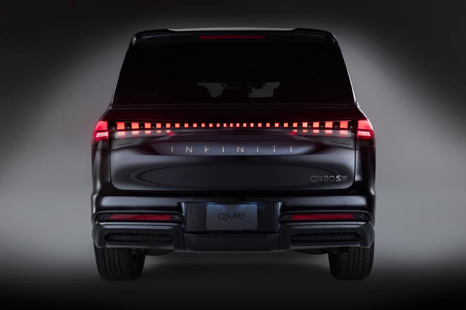Rear view of the 2026 INFINITI QX80 Sport in black, featuring illuminated red taillights, the “INFINITI” name across the back, and the “QX80 S” badge on the right; the vehicle is shown in a clean, well-lit setting.