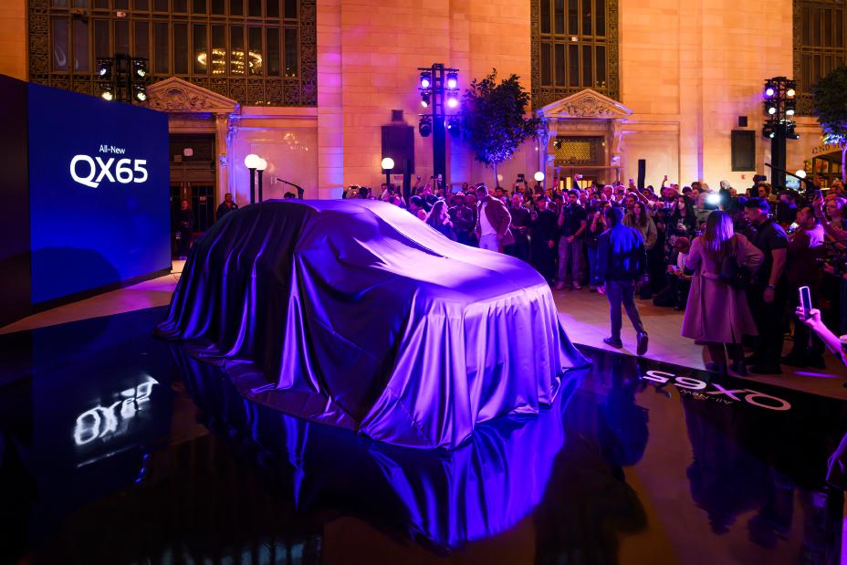 The 2027 INFINITI QX65 hidden under a large cloth under blue light.