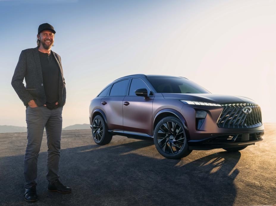 A man standing beside a parked QX65 Monograph during golden hour.