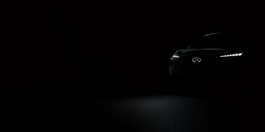 A car is dimly lit only leaving the illuminated INFINITI logo and headlights visible.