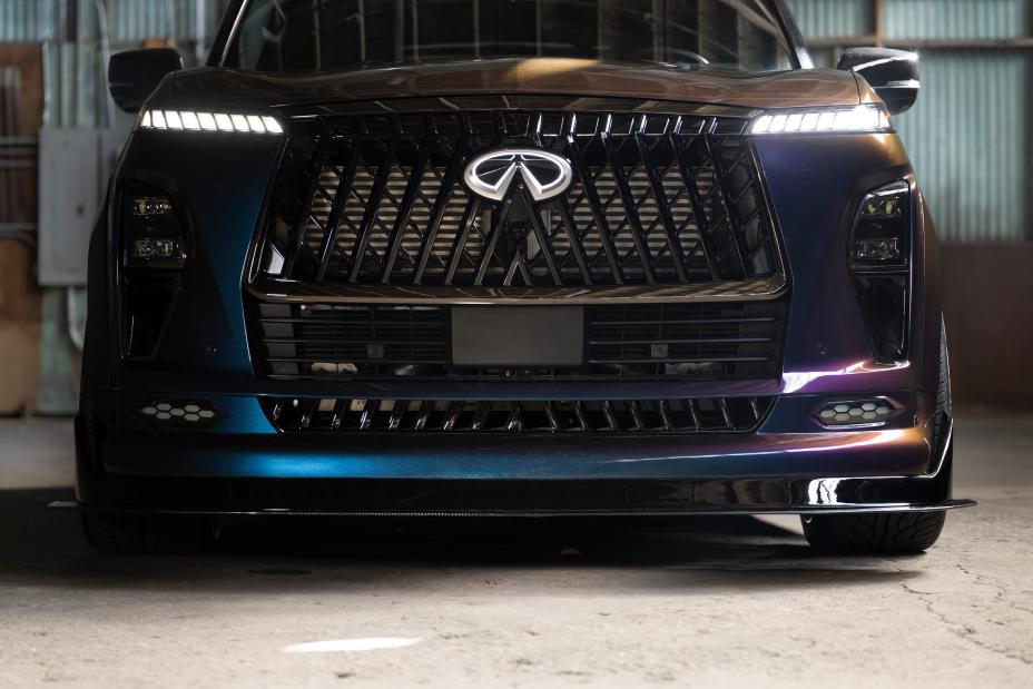 Close up of the front fascia on the INFINTI QX80 R-Spec build, the headlights and emblem are illuminated.