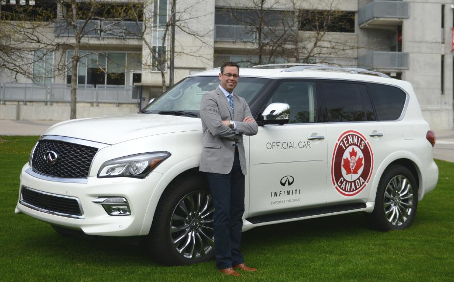 Stephen Lester leaning on a white Infiniti QX80.